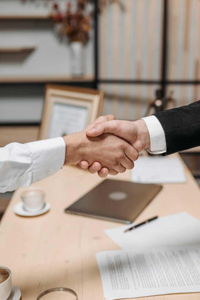 pexels-photo-8112186-8112186 Close-up of two people shaking hands in an office, symbolizing agreement and partnership.